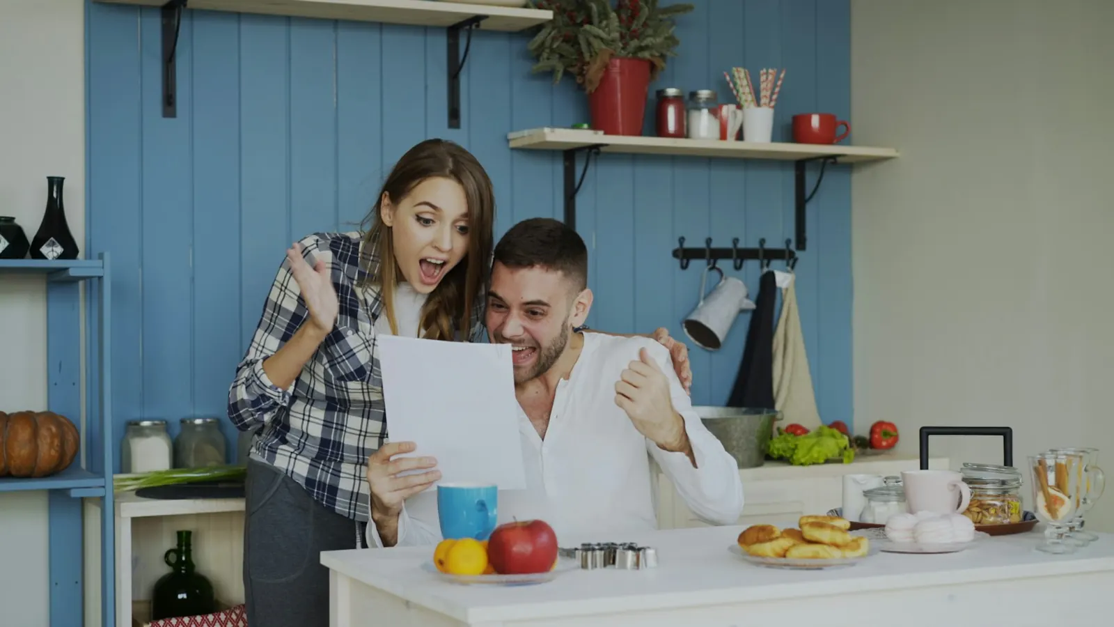 Couple qui se réjouit en lisant un courrier dans sa cuisine